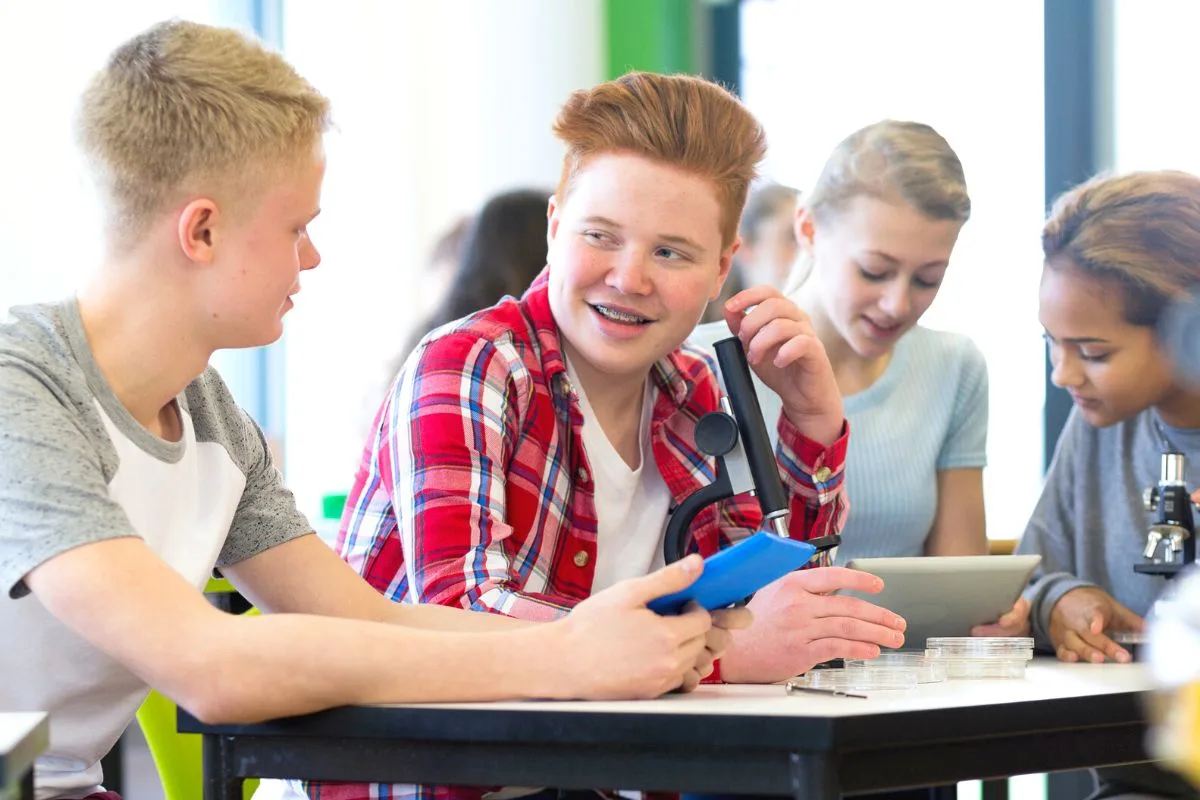two teen students in class smiling, talking through would you rather questions for teen students