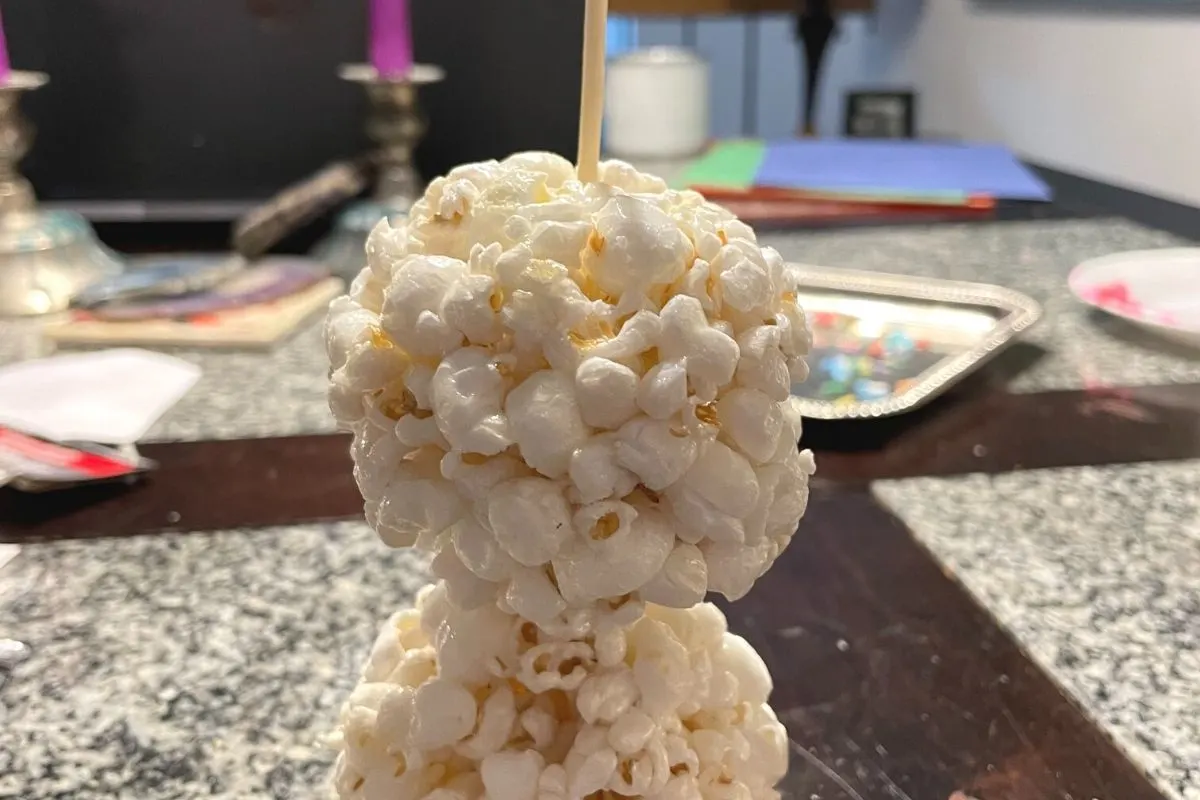 two popcorn balls right on top of each other with a bamboo skewer through the center of them to hold them together