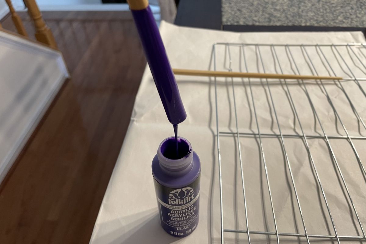 top of chopstick coming back out of purple paint bottle