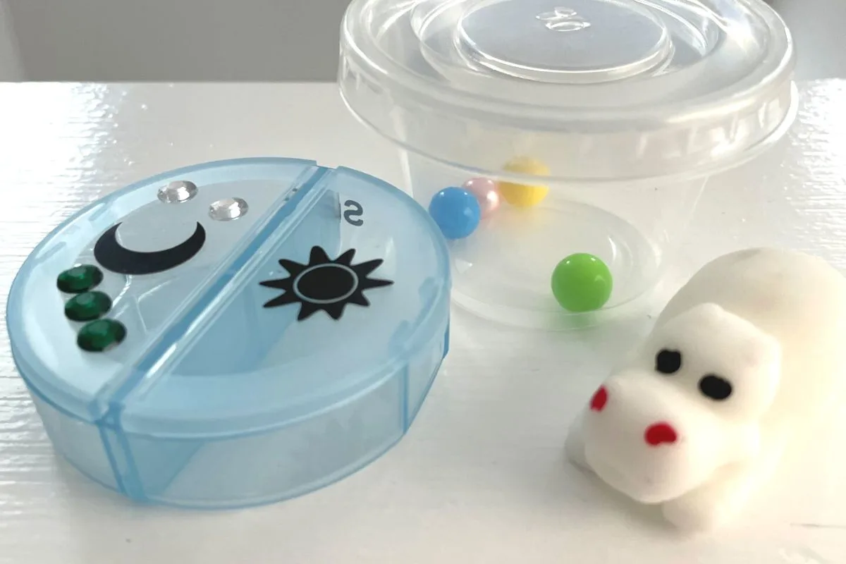 white hippo next to blue pill box and different colored balls representing food