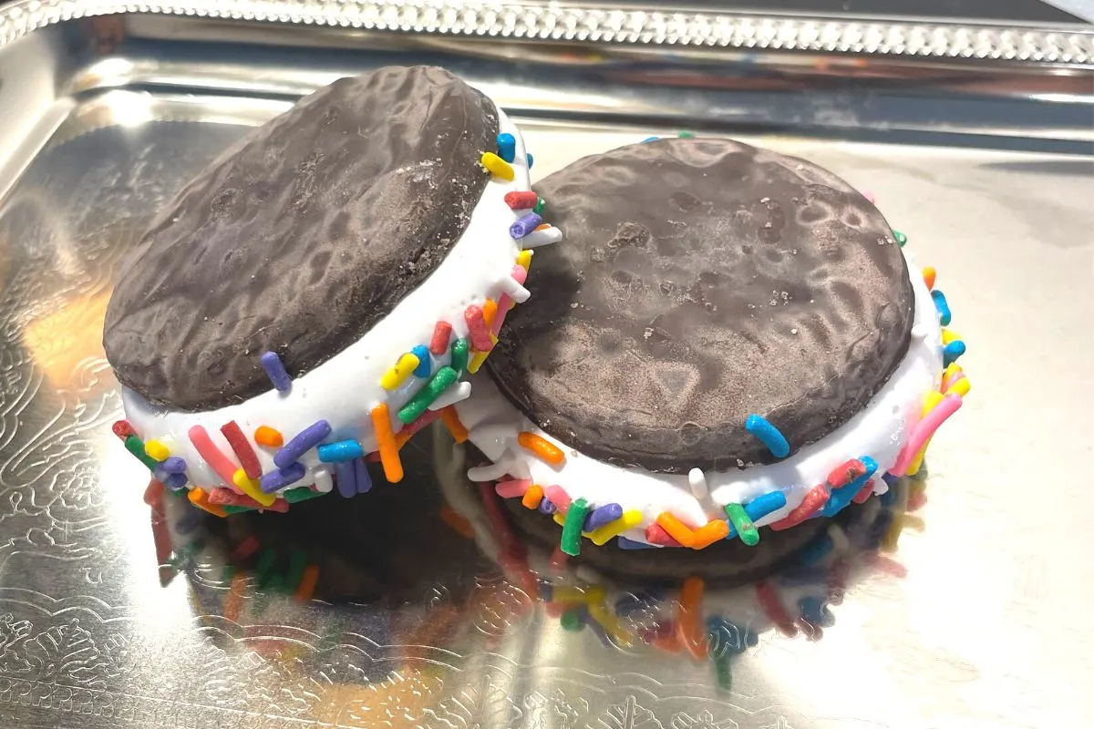 two chocolate cookies filled with marshmallow creme and rainbow sprinkles