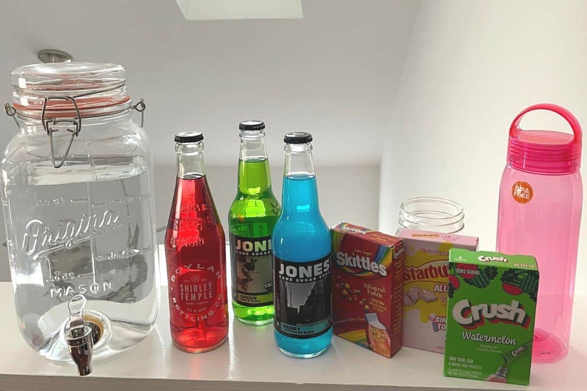 drink mix station with three types of colored sodas, three boxed types of drink mixes (Skittles, Crush, etc.), and a big jug of water plus mason jars