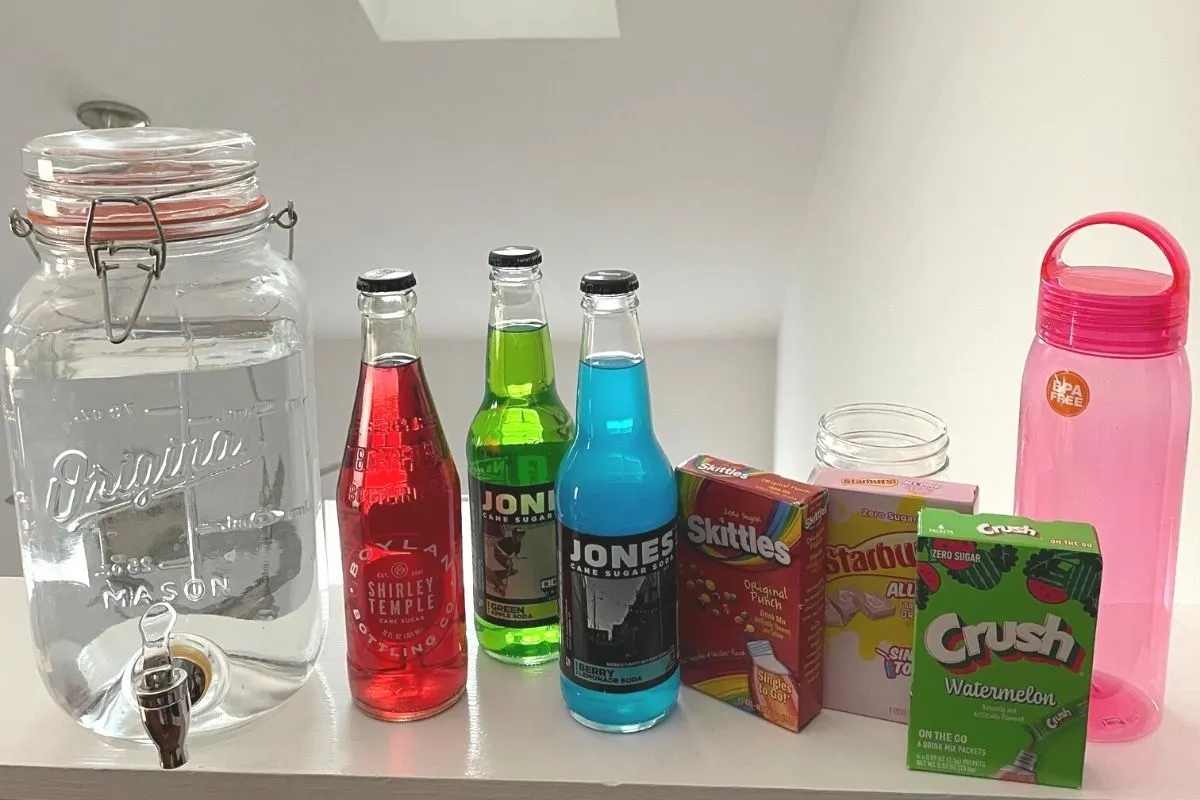 drink mix station with three types of colored sodas, three boxed types of drink mixes (Skittles, Crush, etc.), and a big jug of water plus mason jars