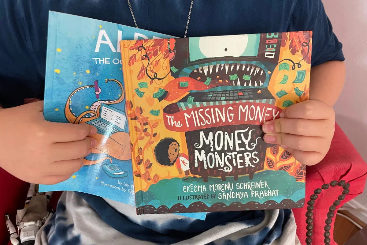 boy in tie-dyed shirt holding The Missing Money Money Monsters book