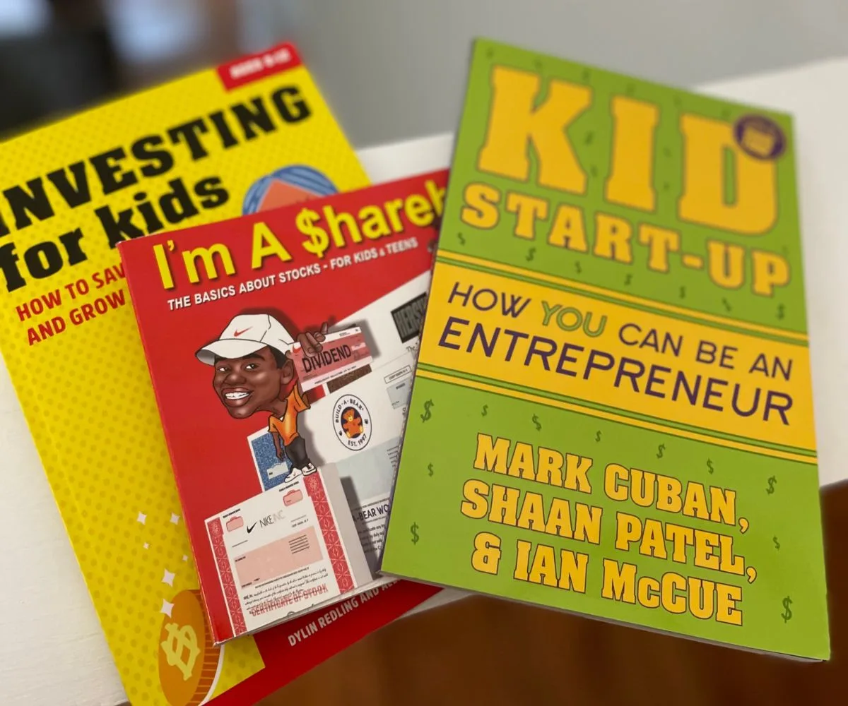three brightly colored books, including Kid Start-Up, on white background
