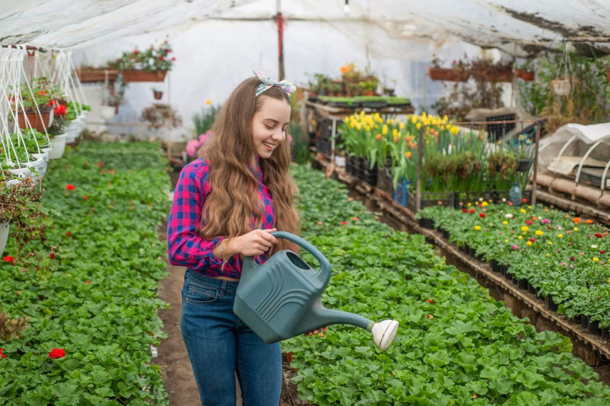 12 year old girl using watering can at local nursery where she works