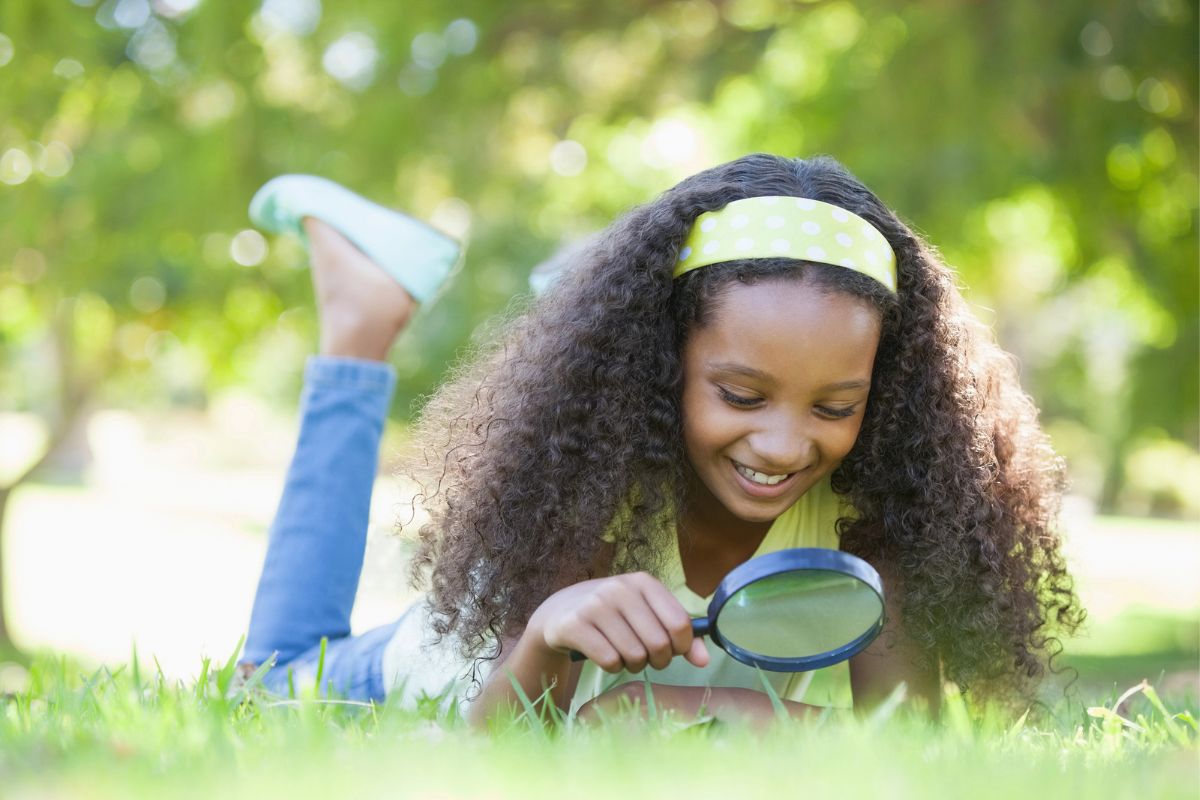 10 year old girl with magnifying glass in backyard for citizen scientist stuff