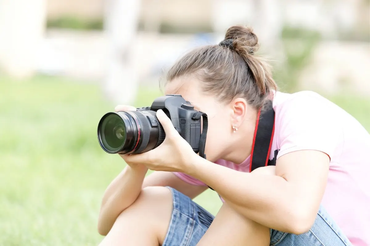 teen girl using professional camera outside in backyard