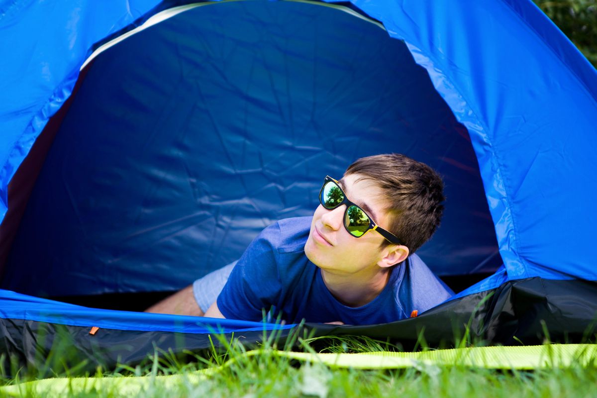 teen boy with reflective sunglasses in a primary blue tent