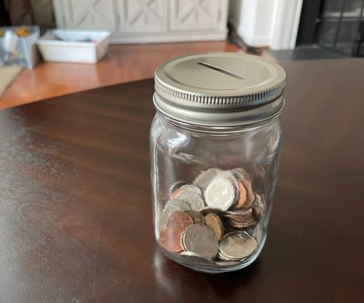 money jar with slot in lid, 1/3 filled with coins