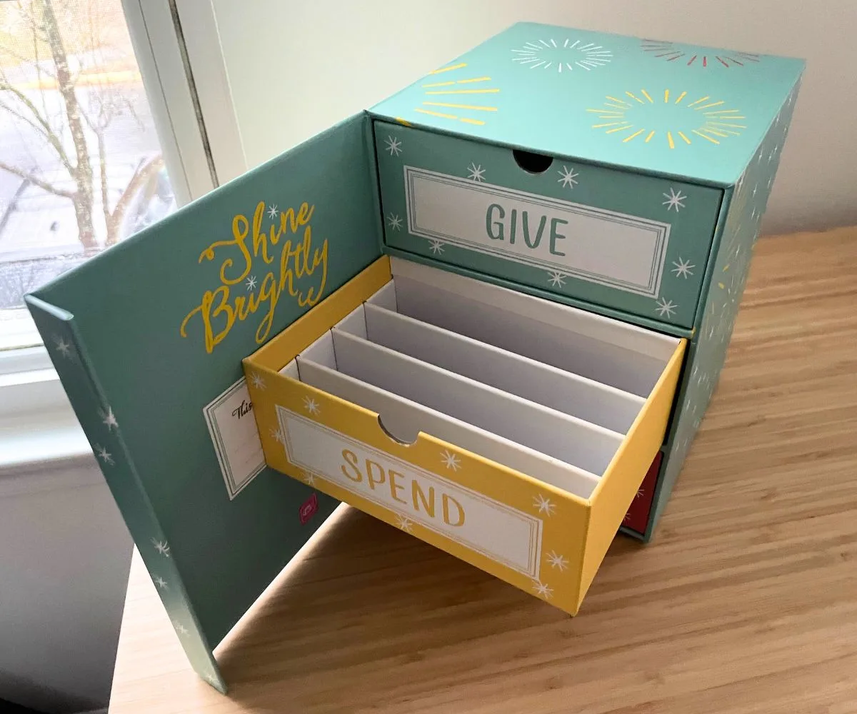 Inside of trio piggy bank box, and the spend drawer is open showing four compartments inside of it