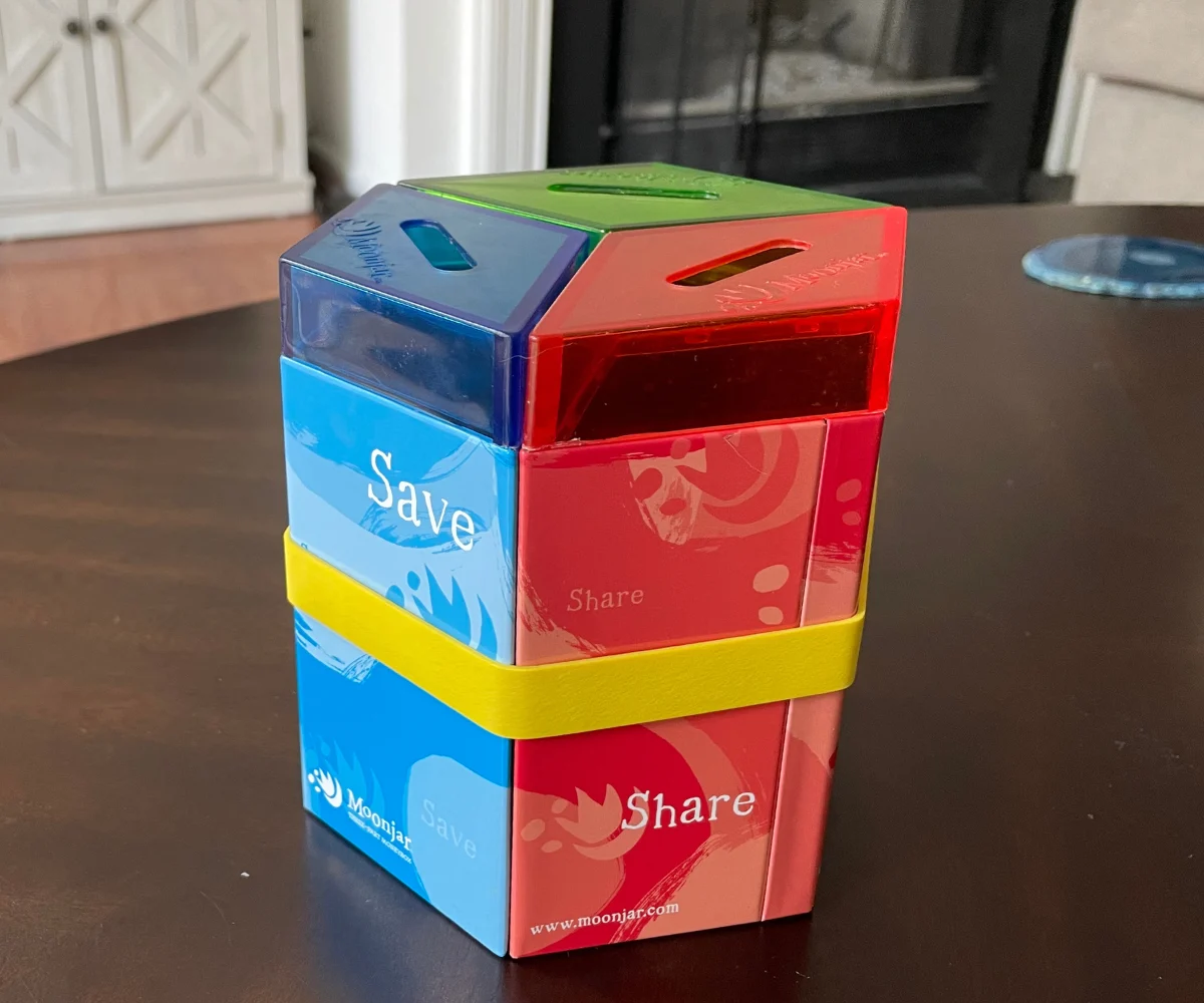 blue, red, and green Moonjar three-part money box on dark table 