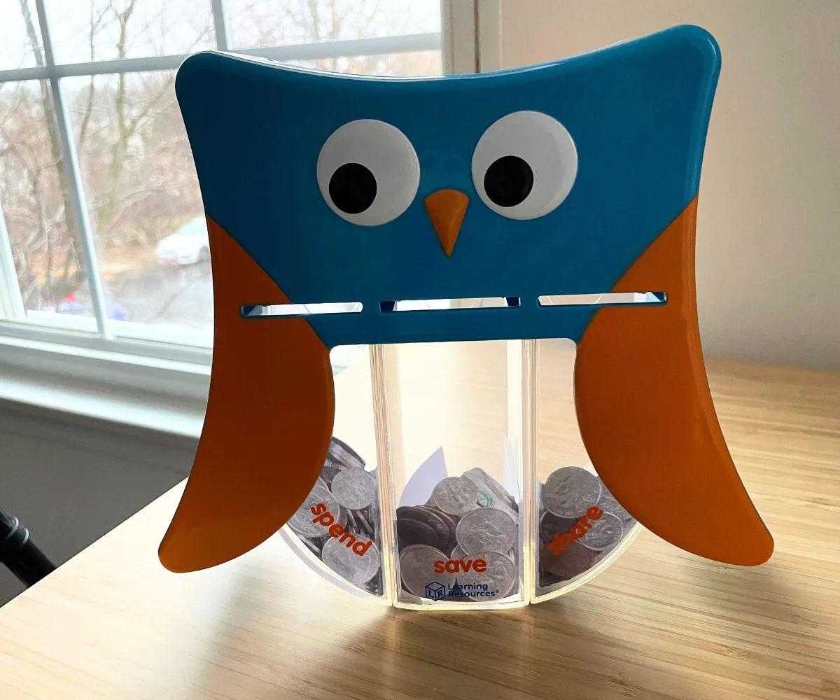 primary blue and orange colored owl bank with three compartments for spend, save, and share