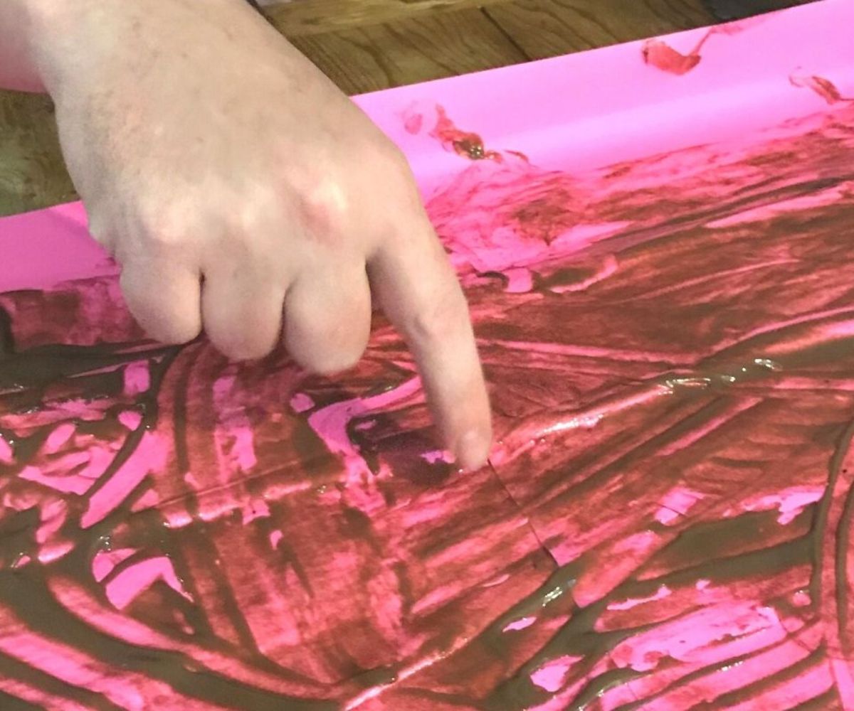 hand playing pudding pictionary on large hot-pink sheet of paper