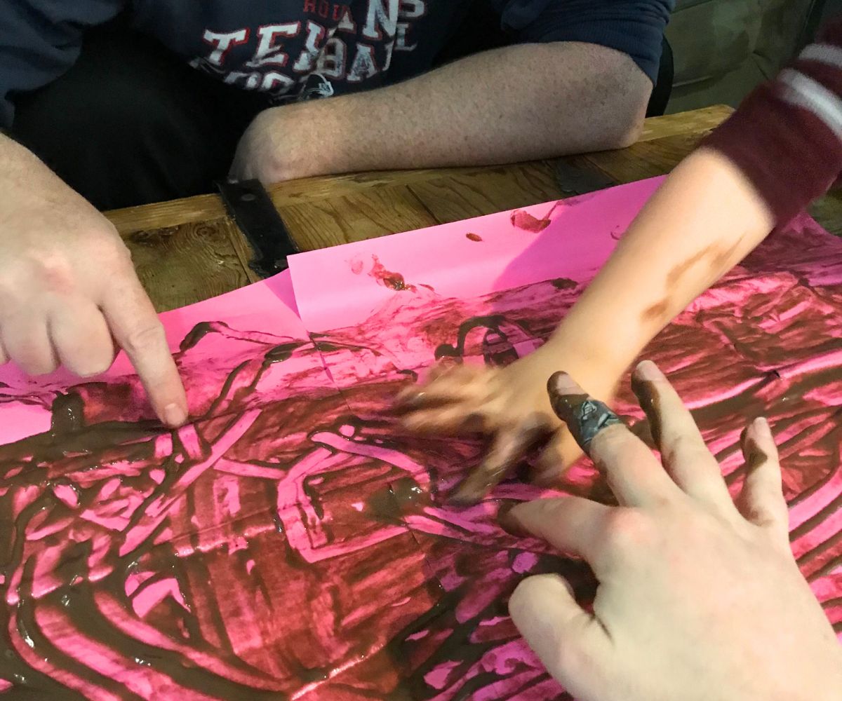 three people playing pudding pictionary on fluorescent pink paper