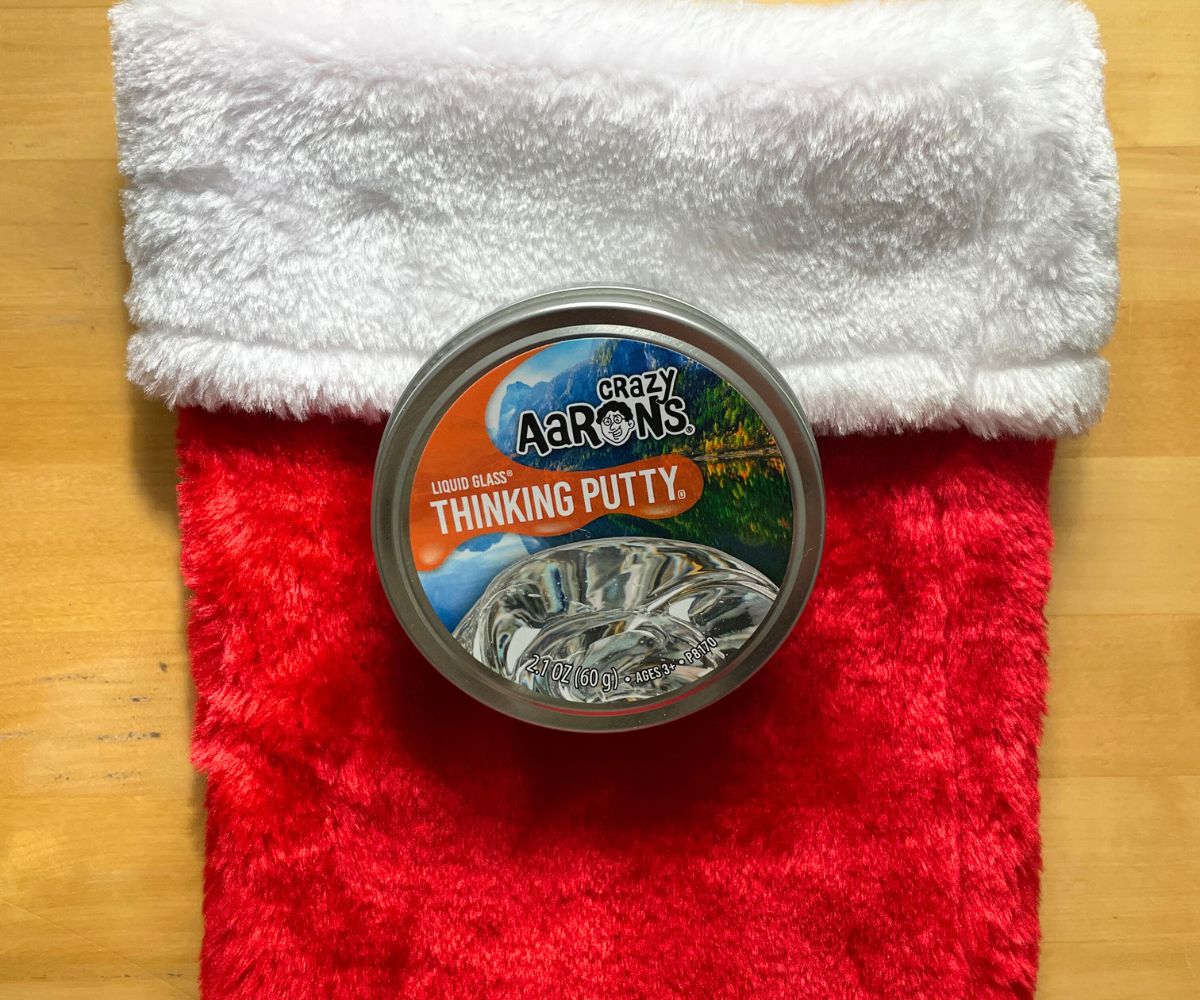 tin of Aaron's Thinking Putty liquid glass on top of red stocking