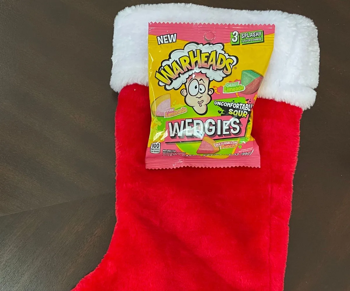 red stocking with white fur, with package of Warheads Wedgies on top