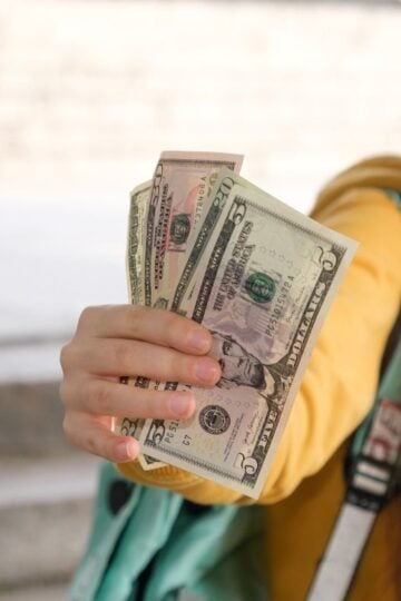 preteen girl in yellow sweatshirt holding money