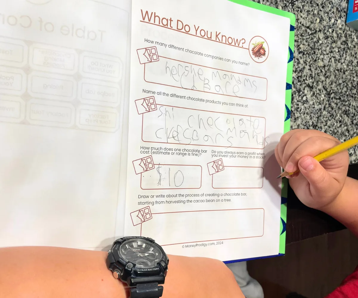 boy's hands filling out What Do You Know worksheet on kitchen table
