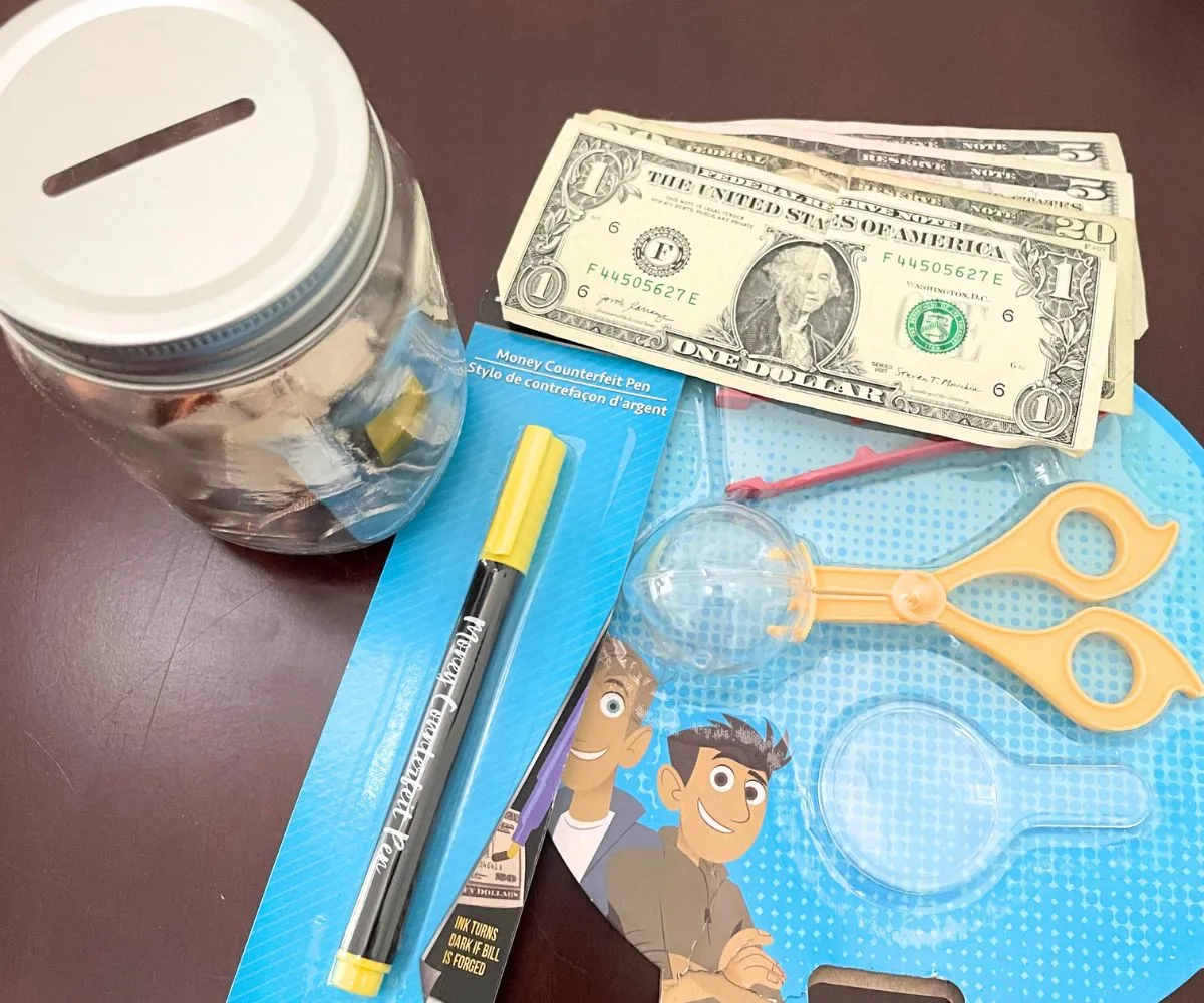 Bug exploring set, money counterfeit pen, jar of coins, and dollar bills on dark background