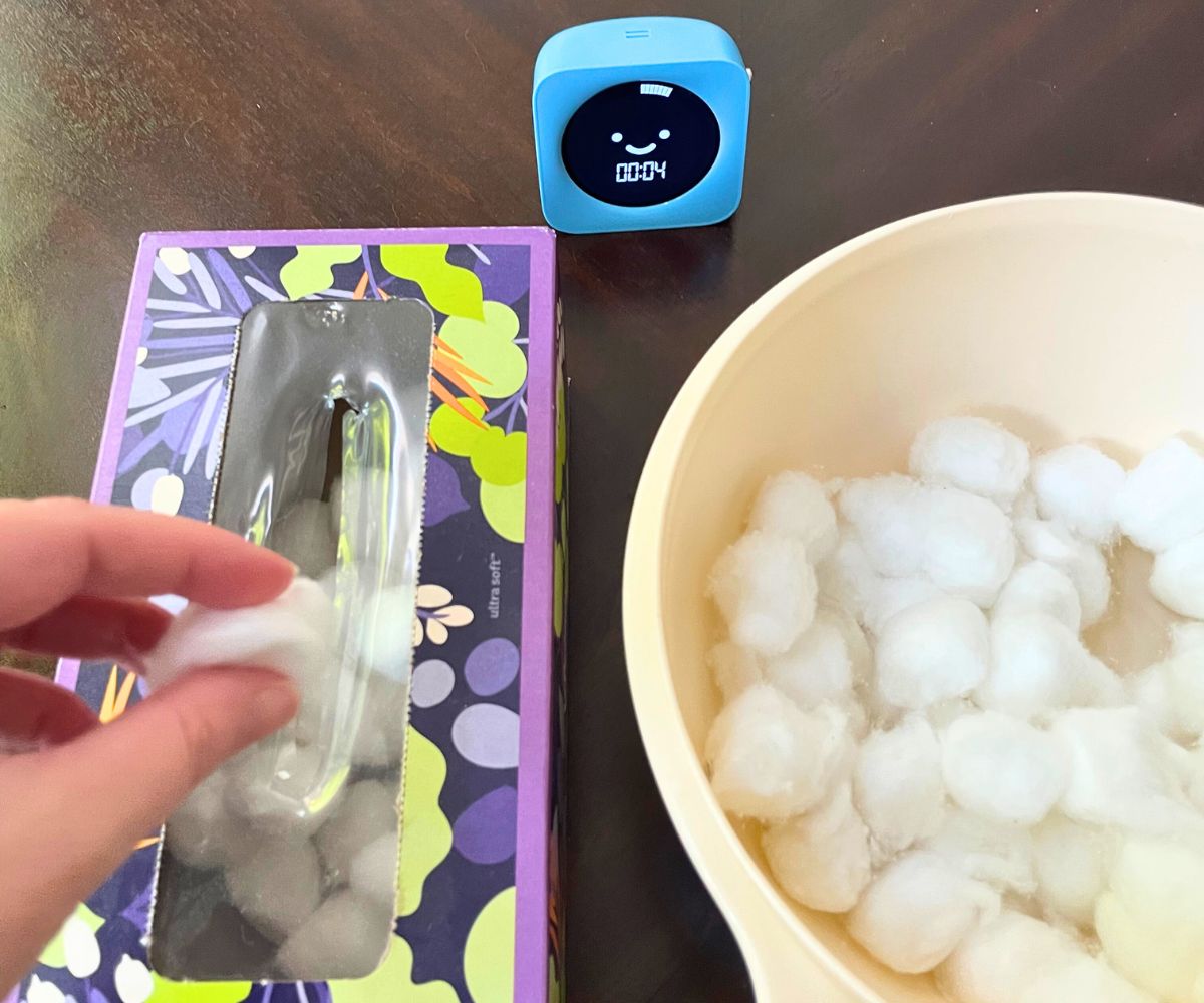 person's hand stuffing cotton balls into tissue box with 4 seconds left on timer