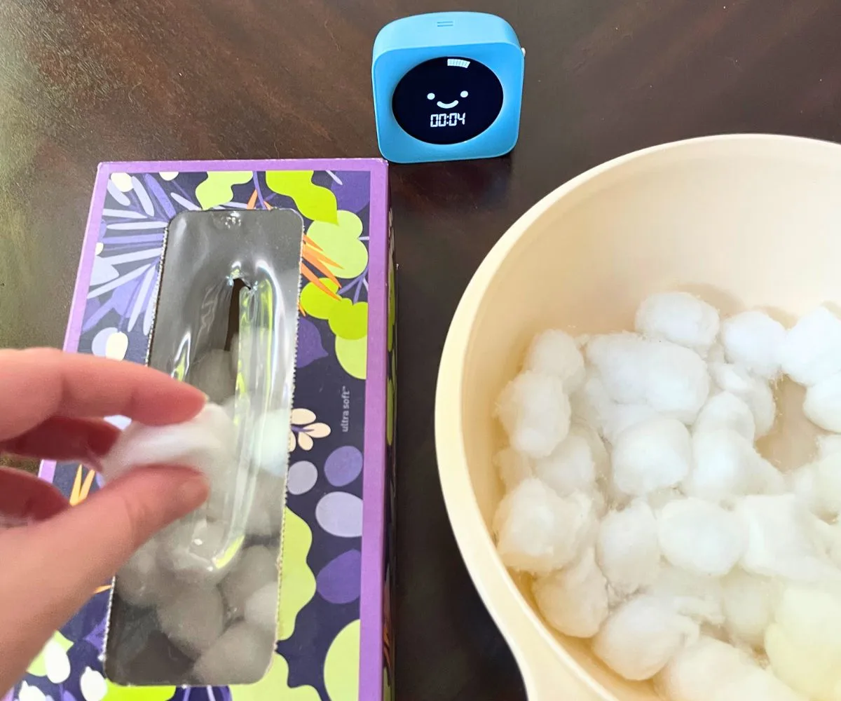 person's hand stuffing cotton balls into tissue box with 4 seconds left on timer