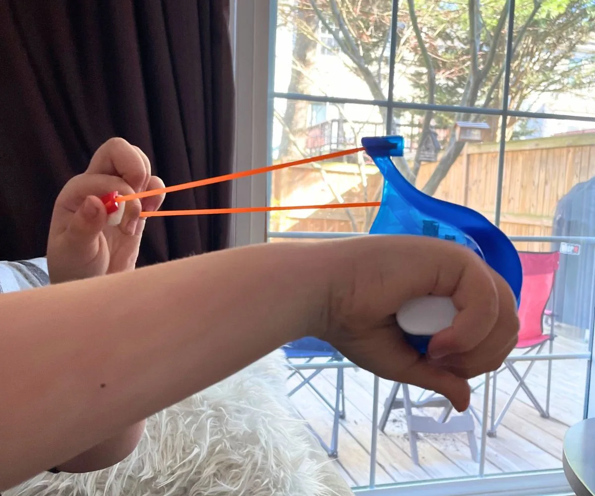 boys hands using marshmallow slingshot blaster with small marshmallow