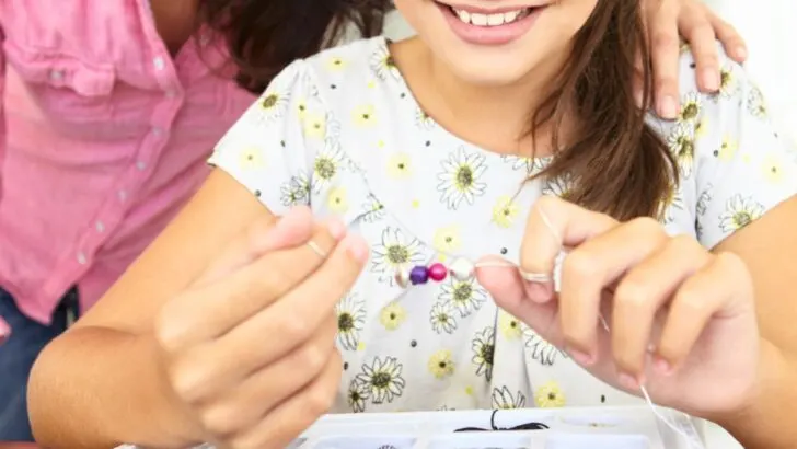 tween girl bead crafting while smiling