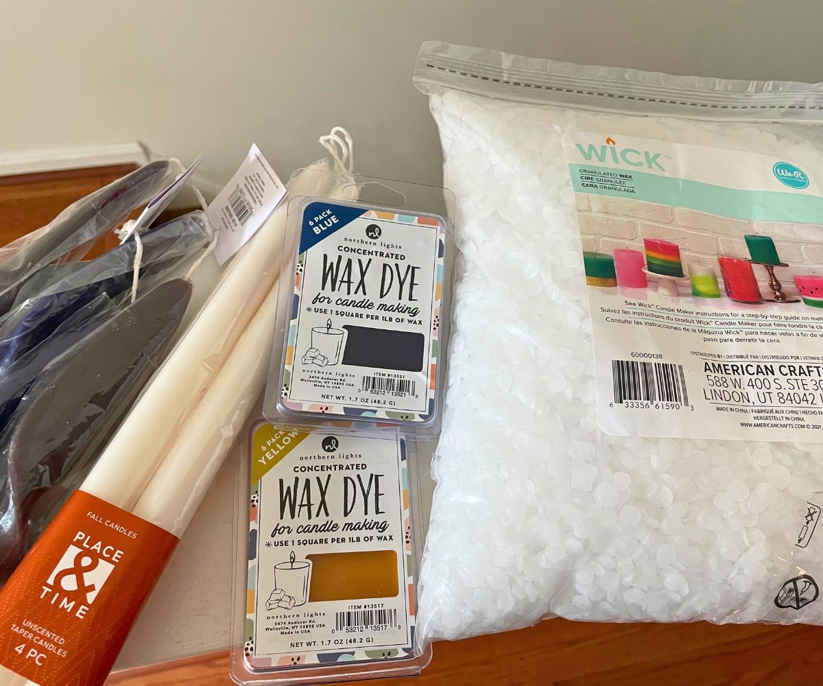 big bag of wax pellets, blank white long candles, and two things of wax dye