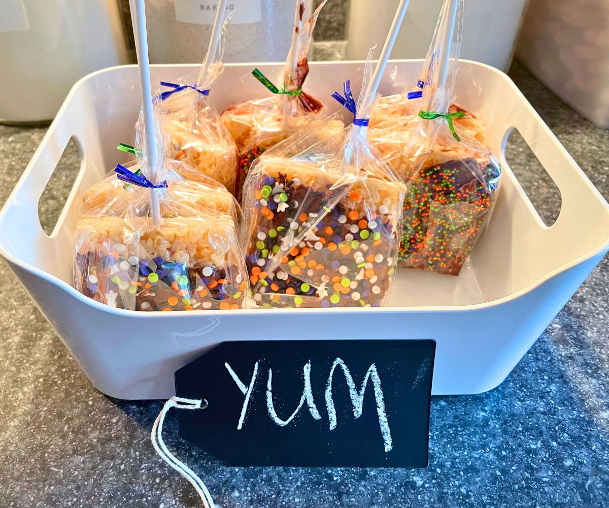 7 rice krispies treats pops upside down sitting in white bin with chalkboard tag "yum"