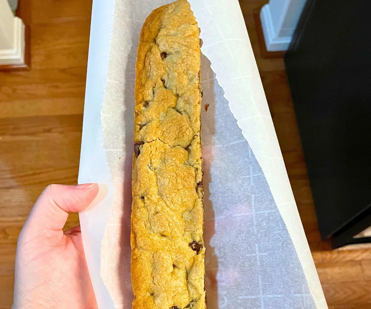 hand holding foot long cookie dough bar in parchment paper