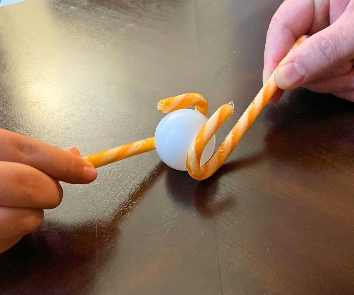 two people with candy cane hockey sticks and a ping pong ball between them