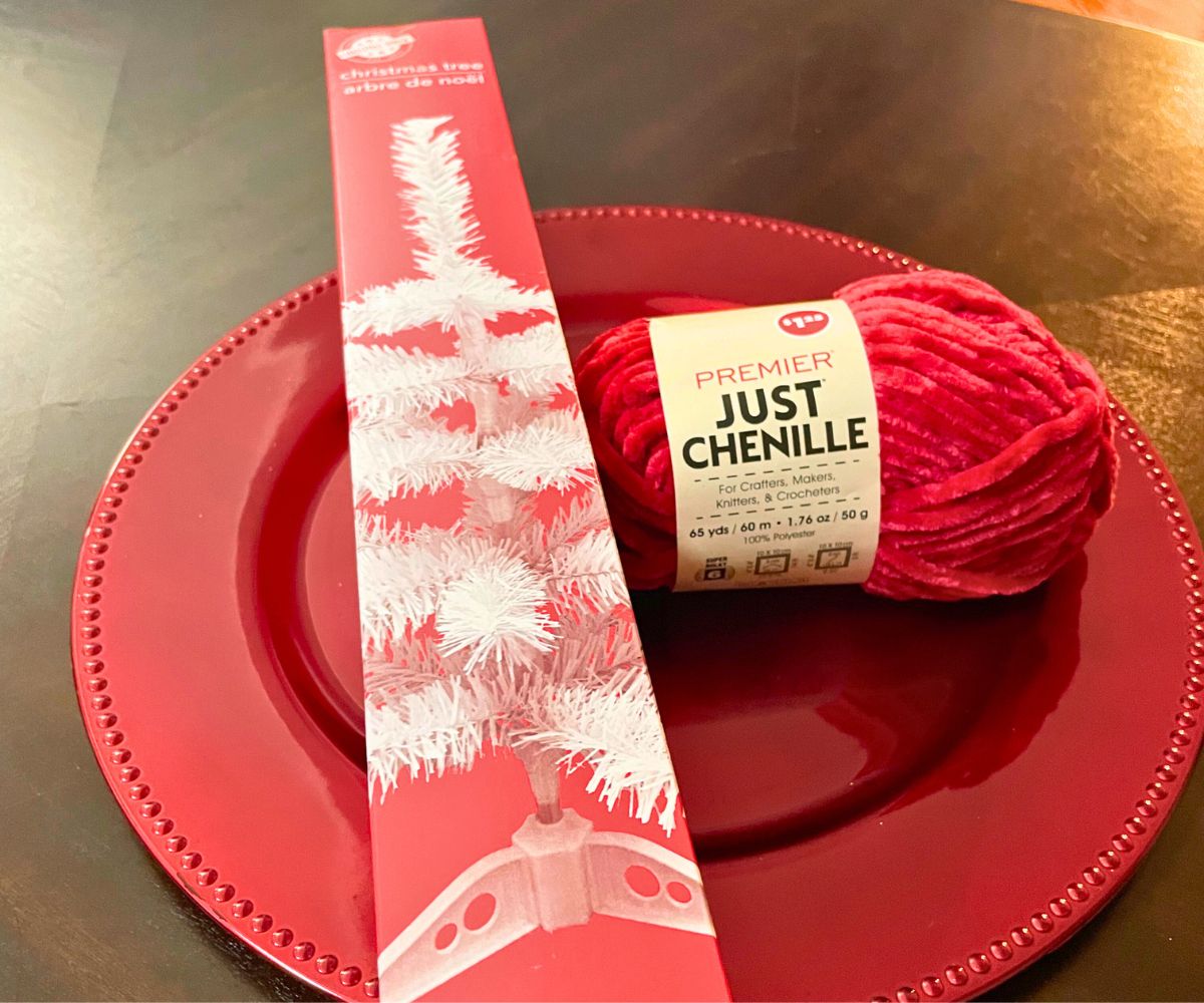 mini box with fake white tree inside, and red yarn, on red plate 