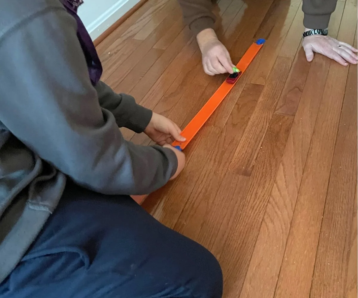 two people building out the race track and transporting the candy in the Hot Wheels with timer