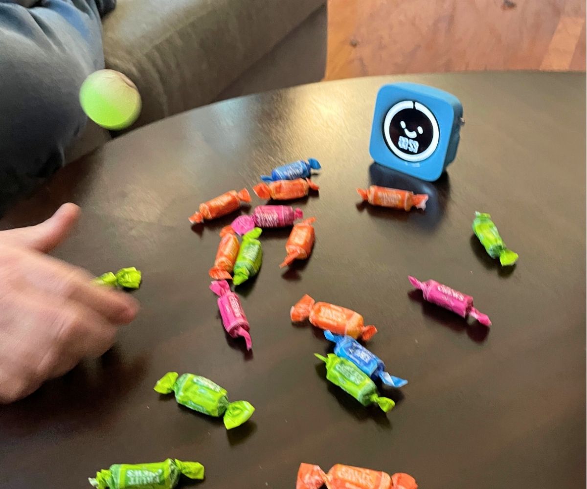 person's hand in motion bouncing the ball and snatching up a candy