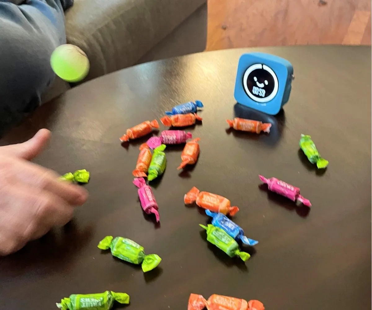 person's hand in motion bouncing the ball and snatching up a candy
