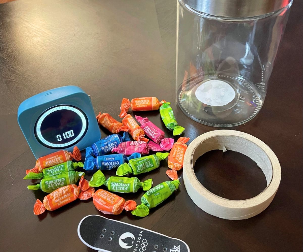 mini skateboard, masking tape, jar, wrapped candies, and 1 minute timer