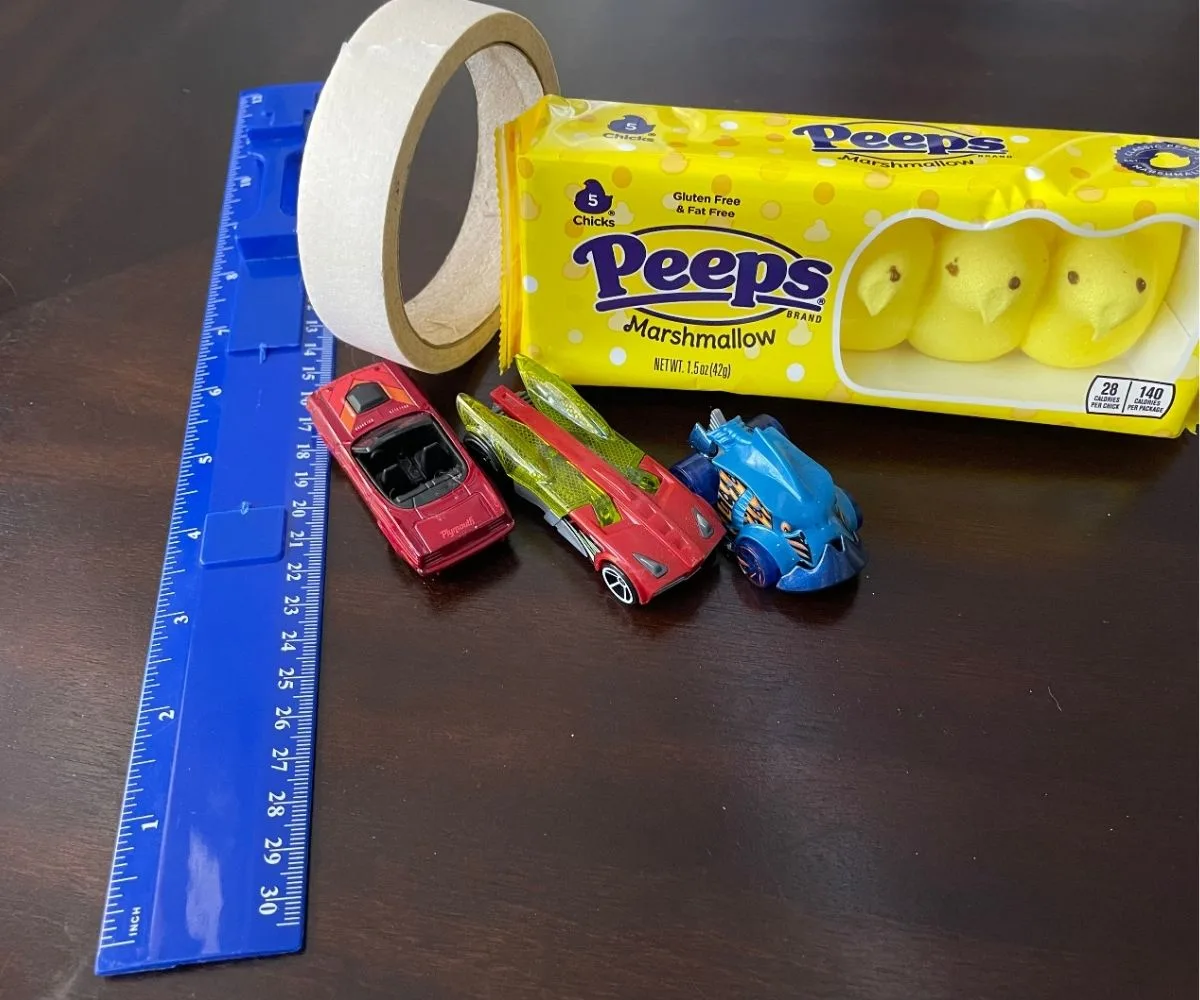 package of bright yellow peeps, three race cars, masking tape, and a ruler