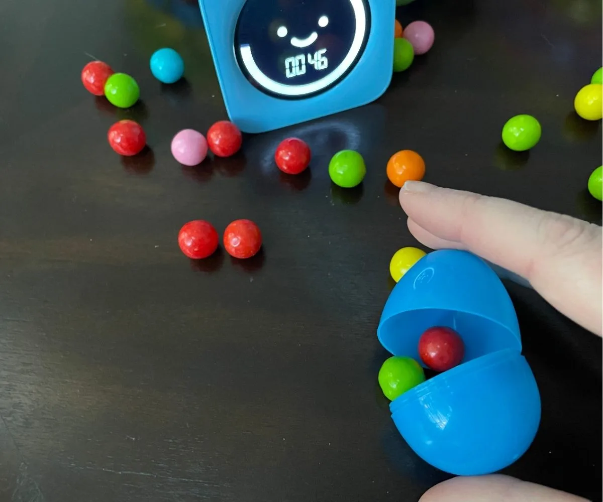 person closing an Easter egg around two gumballs with timer at 46 seconds