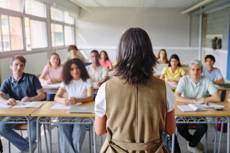 business high school students looking at business teacher in class