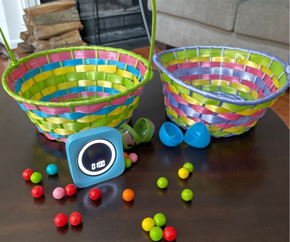 two Easter egg baskets with scattered colorful gumballs, one-minute timer, and two opened, empty Easter eggs