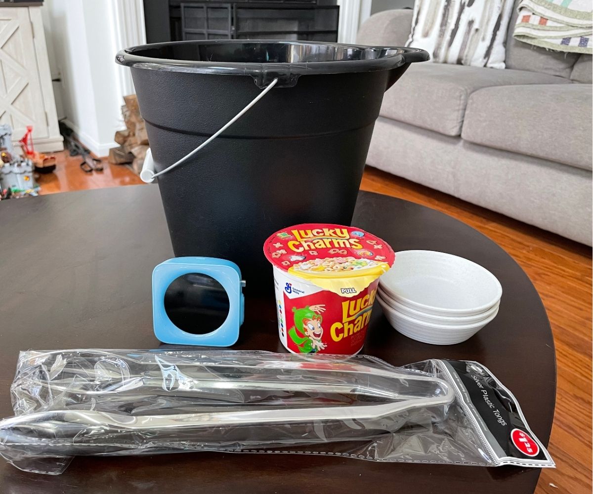 black bucket, timer, Lucky Charms container, three smaller containers, and silver tongs