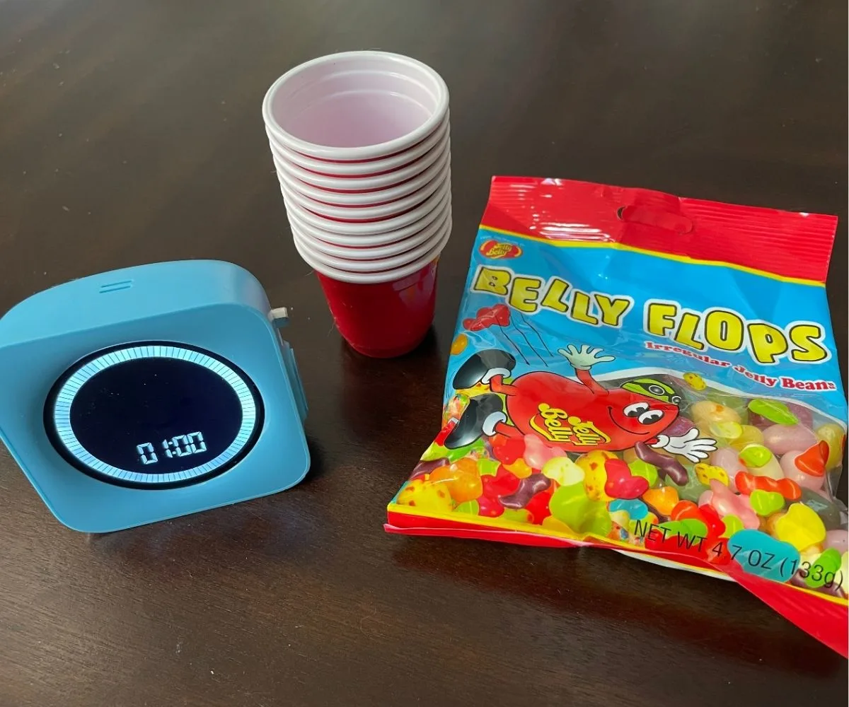 package of Jelly Belly bean flops, timer set at 1 minute, and stack of mini red cups