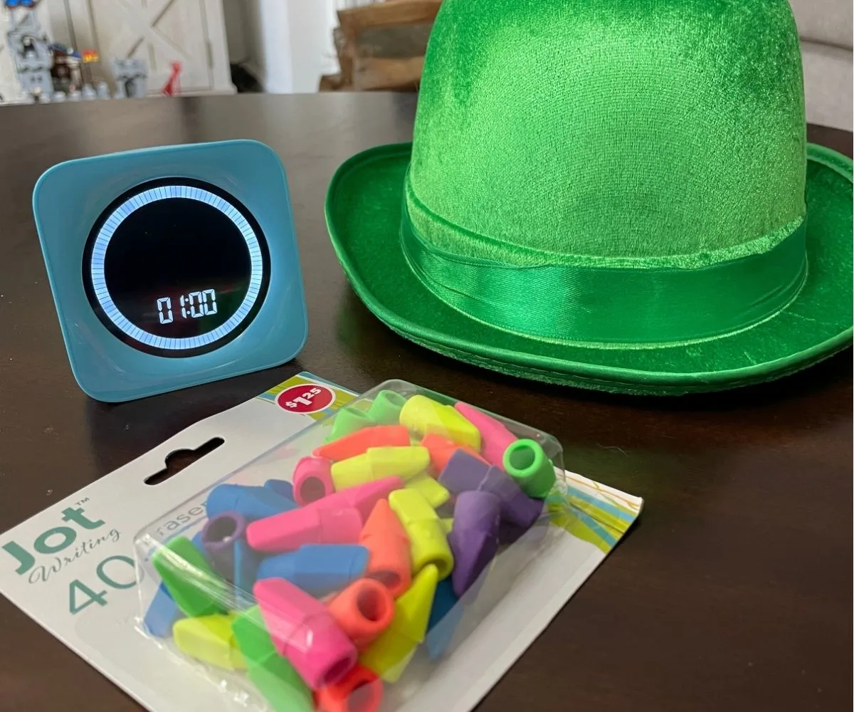 big green leprechaun hat, timer set to 1 minute, and container of colorful pencil eraser tops