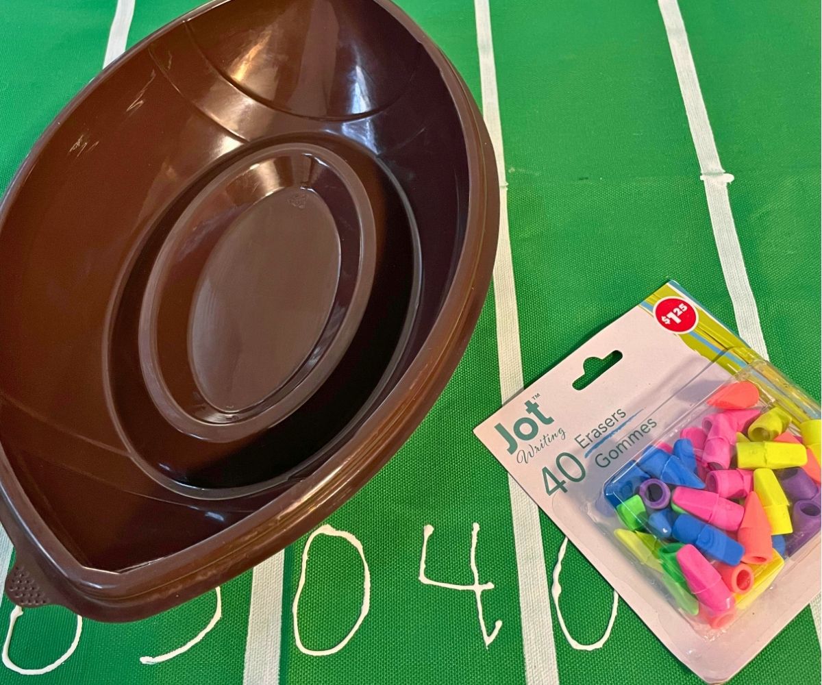 empty football snack container next to colorful pencil erasers on field tablecloth