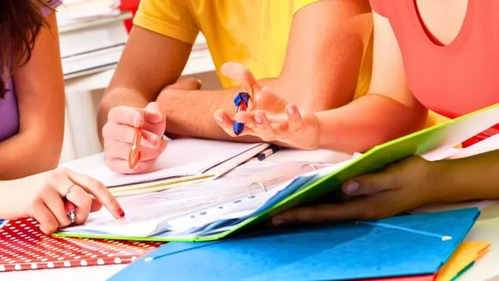 three teens in brightly colored shirts working on budgeting printables