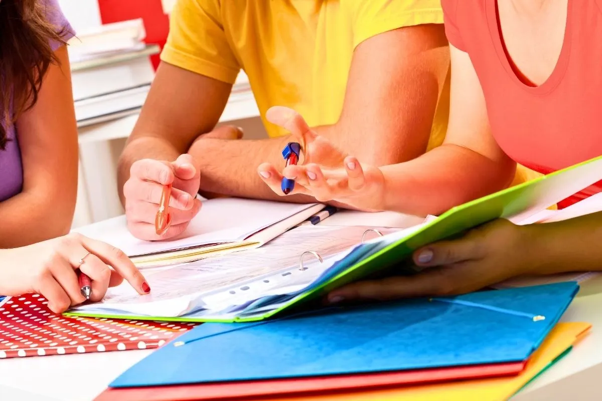 three teens in brightly colored shirts working on budgeting printables
