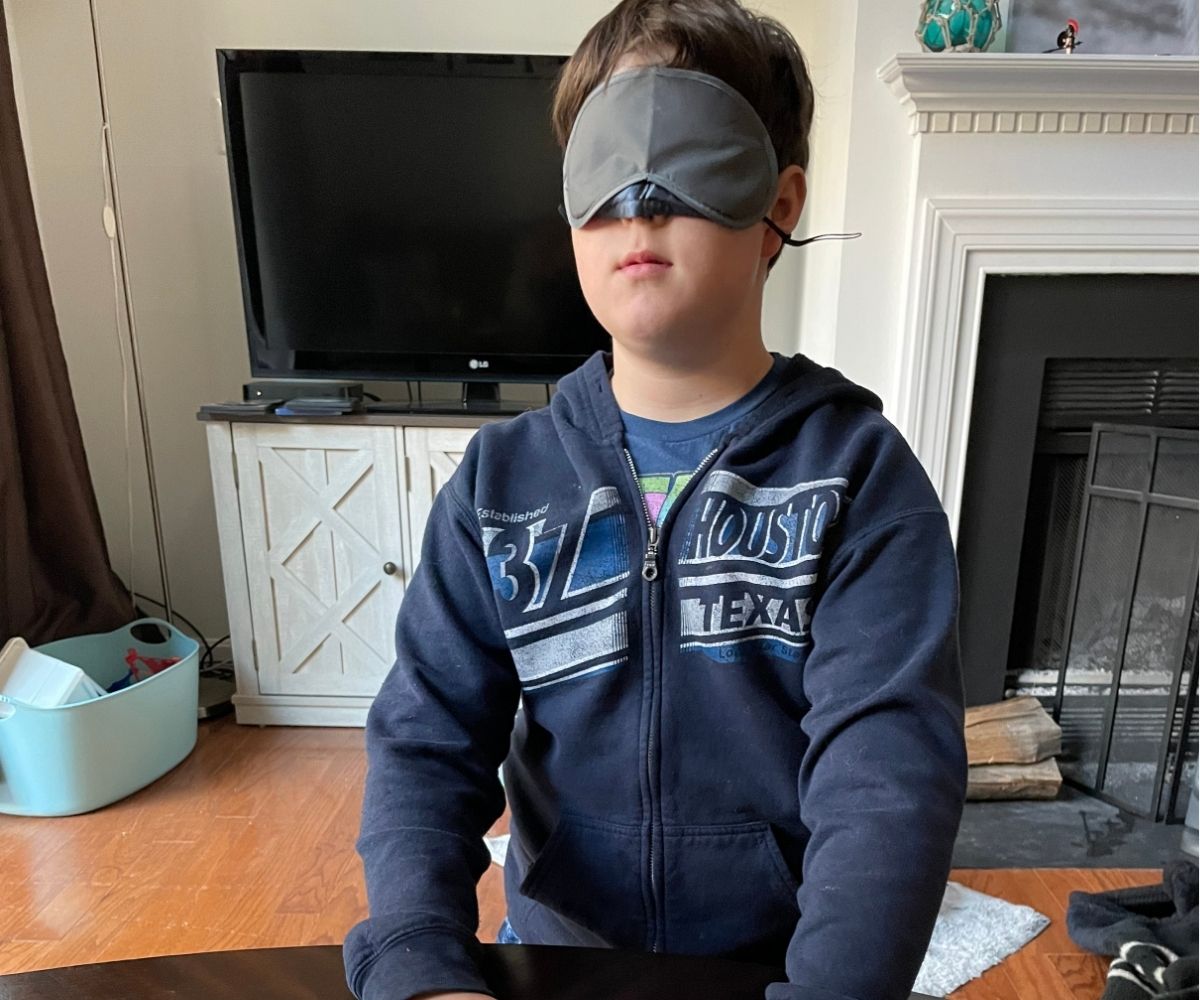 blindfolded tween boy with hands on table