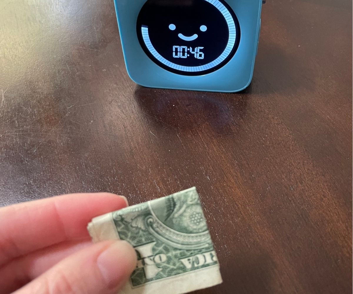 dollar bill in someone's hand folded to a square, timer showing 00:46 seconds left