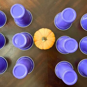 three rows of dark purple cups upside down with mini pumpkin on table